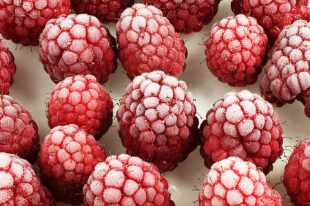 Frozen raspberries covered in frost, showcasing their vibrant red color and unique texture.
