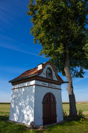 small chapel (roadside shrine) next to the road. Silesian area of Poland, RacibÃ³rz. Blue sky, sunny day, summer.の写真素材