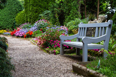 Romantic park alley with flowers and wooden benchの写真素材