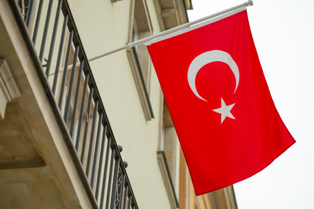 The Turkish flag is fluttering on the wall of the building against the overcast sky