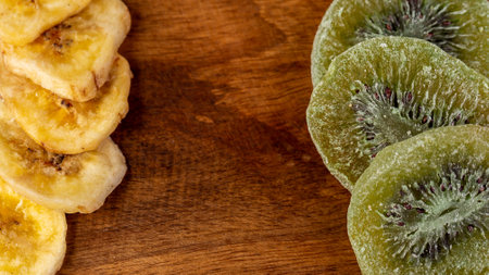 Slices of candied kiwi and babanas on a chopping boardの写真素材