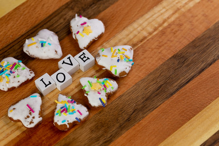 A composition of glazed gingerbreads in the shape of hearts and the word "Love" arranged on a wooden boardの写真素材