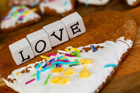 A composition of glazed gingerbreads in the shape of hearts and the word "Love" arranged on a wooden boardの写真素材