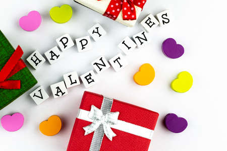 Happy Valentines text arranged from wooden blocks on white background accompanied by gift boxes