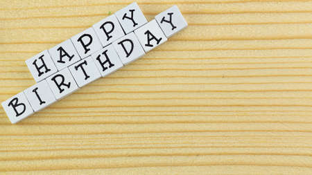 The text happy birthday arranged from blocks on a wooden background