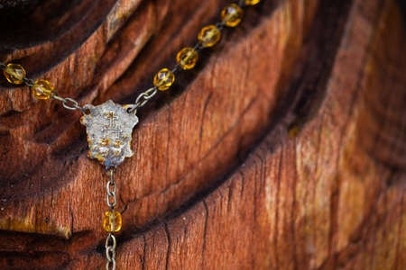 A cheap aluminum cross hung on a wooden statue of the Virgin Mary. Natural light, object in the shadowの写真素材