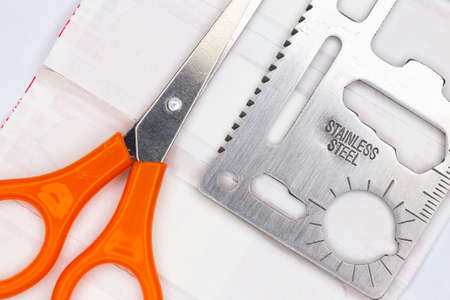 Emergency kit with bandage materials, scissors and multitool. artificial light from above, top shot...