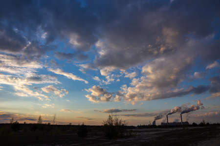 A view of the smoking chimneys of a coal-fired power plant against the backdrop of a dramatic sky...