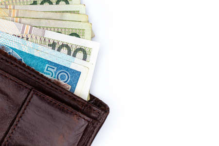 Lots of Polish banknotes sticking out of a brown leather wallet. Photo taken under artificial, soft...