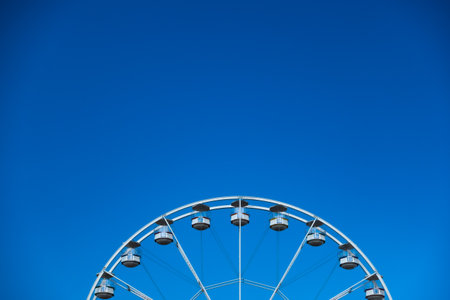 A white ferris wheel against a blue sky background. Photo taken in good lighting conditionsの写真素材