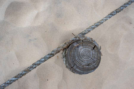 A wooden post with stretched ropes separating the hiking trail from the protected area. Photo taken in good lighting conditions on a cloudy dayの写真素材