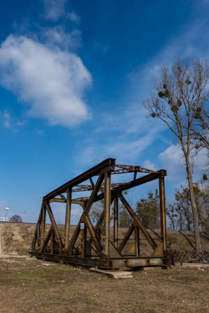 Rusty spans of the old railway bridge have been dismantled. Perspective photo taken on a sunny day.