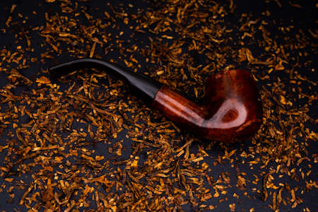 A smoking pipe against the background of scattered tobacco.の写真素材