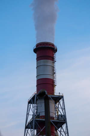 The smoking chimneys of the power plant against the slightly cloudy sky. Soft light, made in the...