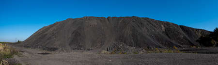 A pile of mineral material in black coal recovery plants. Photo taken on a sunny day, the black of the coal contrasts with the blue of the sky.の写真素材