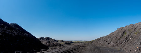 A pile of mineral material in black coal recovery plants. Photo taken on a sunny day, the black of the coal contrasts with the blue of the sky.の写真素材