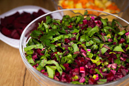 Fresh, chopped beetroot leaves arranged in a glass bowl. Photo taken under artificial, soft light.の写真素材