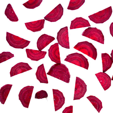 Lots of particles of a freshly cut beetroot scattered casually on a white background. Photo taken...