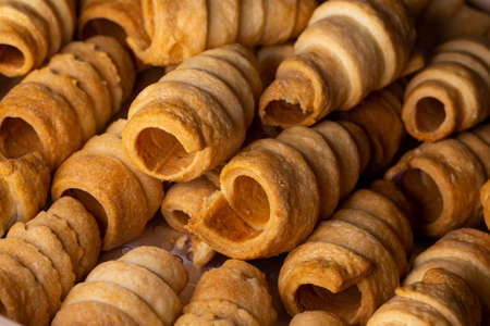 Lots of sweet home made confectionery tubes prepared to be filled with cream. Photo taken under soft...
