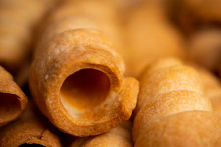 Lots of sweet home made confectionery tubes prepared to be filled with cream. Photo taken under soft artificial light.の写真素材