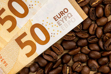 Roasted coffee beans together with 50 euro bill. High price of coffee. Pictute taken in good artificial light.の写真素材