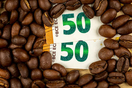 Roasted coffee beans together with 50 euro bill. High price of coffee. Pictute taken in good artificial light.の写真素材