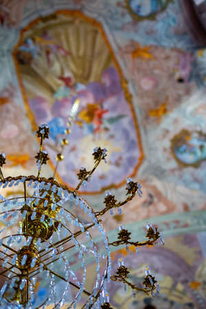Beautiful crystal chandelier in the church. In the background, a blurry, richly ornamented vault....