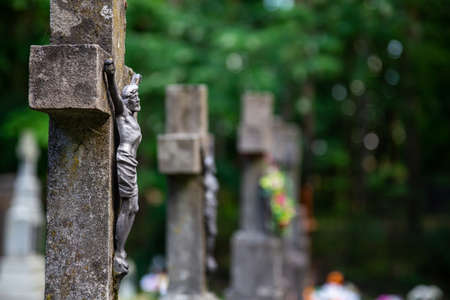 Jesus figurine on the cemetery cross. Picture taken in a soft light, shaded place.の写真素材
