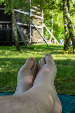 First-person view of the legs and feet of a man relaxing on the grass in a city park. Photo taken on a sunny day in natural light.の写真素材