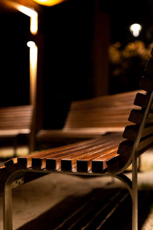 A park shed with empty benches during a pandemic. Meeting places without people. The photo was taken at night with artificial street lighting.の写真素材