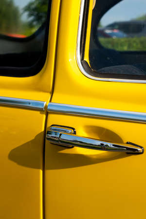 A door handle on a yellow restored classic car. Photo taken in natural light.の写真素材