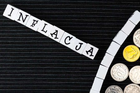The wording inflacja translated as inflation and Polish coins and banknotes on the black background....