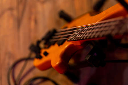 An electric bass guitar based on a stand placed on the stage. The subject is illuminated by bright,...