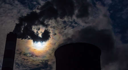 A close-up of the smoke and steam coming out of the chimneys of a coal-fired power plant. The photo...