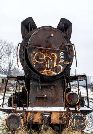 Old, rusty, demolished steam locomotive standing on the side track of the train station. Picture...