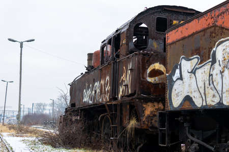 Old, rusty, demolished steam locomotive standing on the side track of the train station. Picture taken in cloudy winter day.の写真素材