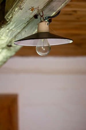 Old electric lamp on the ceiling of an abandoned wooden house. Photo taken in low light conditions.の写真素材