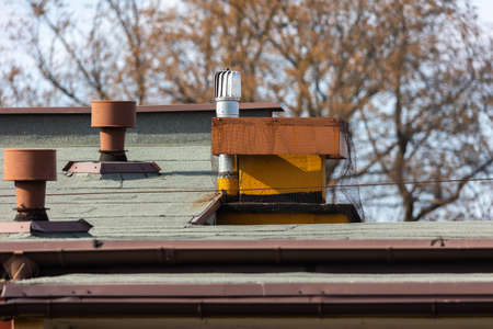 Ventilation equipment on the roof of the building against blurry background. Chimneys covered with...