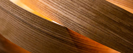 A close-up of a room lamp made of veneer strips. The object is illuminated by atmospheric light