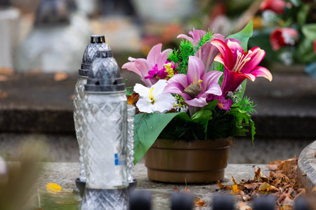 Candles and flowers on graves in the cemetery during the All Saint's Day. Taken during the day,...