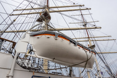 A white lifeboat on the side of a sea sailing ship. Life-saving equipment for seafarers during a...