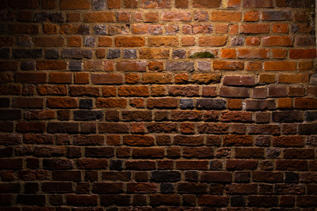 A red brick wall illuminated at night. Surface texture emphasized by the angle of incidence of light