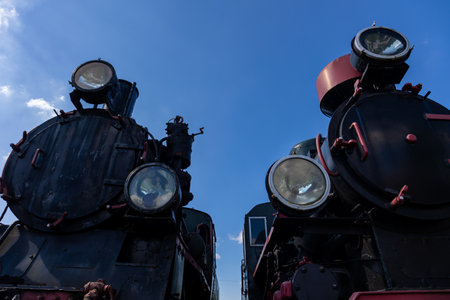 Front view of two steam locomotives standing side by side. Bottom view showing objects against a...