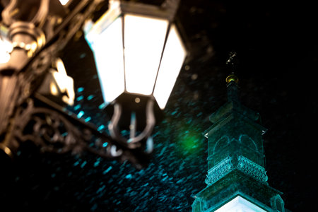 Illuminated catholic church tower in the evening during a heavy snowfall. Blurred snowflakes in the...