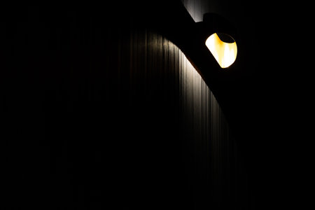 Close-up of mood lighting in a dark room. Black walls finished with panels with a grooved structureの写真素材