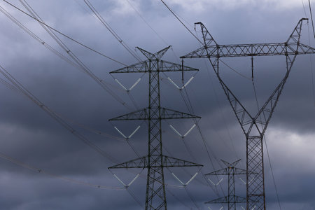 The silhouette of a high-voltage pylon against a dramatically cloudy sky. Development of...