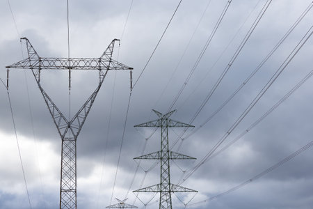 The silhouette of a high-voltage pylon against a dramatically cloudy sky. Development of high-voltage transmission networksの写真素材