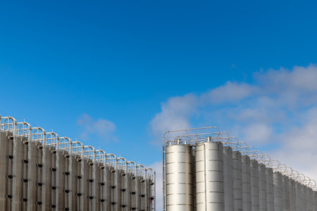 Stainless steel silos against the blue sky. Warehouses for storage of plastics and bulk grains.の写真素材
