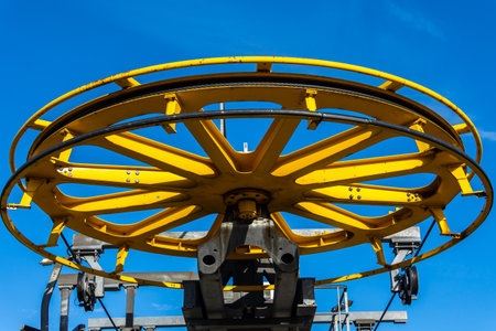 Details of the construction of a mountain chairlift. View of a large drive wheel against a blue sky