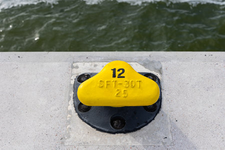 Yellow mooring hook on the concrete quay. Safety of boats moored to the waterfront. Photo taken on a...